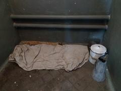 Prison cell with bed and basic furniture