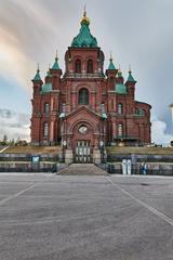 Uspenski Cathedral in Helsinki with red brick facade and green domes under blue sky