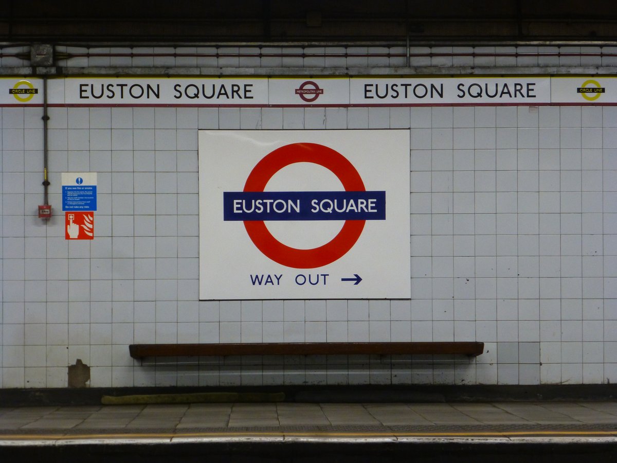 Grey platform wall tiling and historic Metropolitan and Circle Lines station frieze at Euston Square station