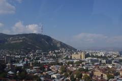 Panoramic view of Tbilisi cityscape with mixed old and modern buildings under a clear sky