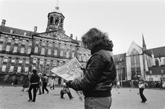 Girl reading morning newspaper with large headline on the Dam square in Amsterdam during Queen Juliana's abdication