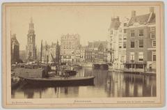 View of the Amstel River from Halvemaansbrug towards Muntplein with historic buildings including the Munttoren and the corner building of 'De Nederlanden van 1845'