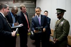 President Barack Obama looking at pictures of Major Reggie McClam's twin girls in a service elevator with his staff at Fontainebleau Resort Miami 2011