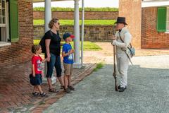 Soldier in beige uniform and top hat talks to children and woman at Fort McHenry National Monument
