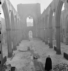 Ruined interior of St George's Cathedral in Southwark with priest standing amidst bomb damage in 1942