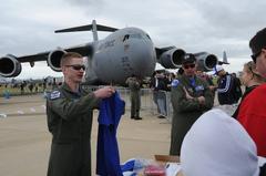 U.S. Air Force 1st Lt. Brett Vongroven showing squadron shirt to fan beside F-22 Raptor jet at Australia International Airshow 2011