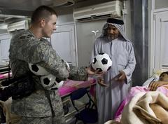 Senior Airman Robert Aten distributing soccer balls to Iraqi families during free cleft lip and palate surgeries
