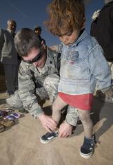 U.S. Air Force Lt. Col. Thomas Knolmayer fitting shoes on Afghan girl at Parwan Refugee Camp