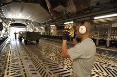 U.S. Air Force Staff Sgt. marshaling a Humvee into a C-17 Globemaster III during engine running on/off competition