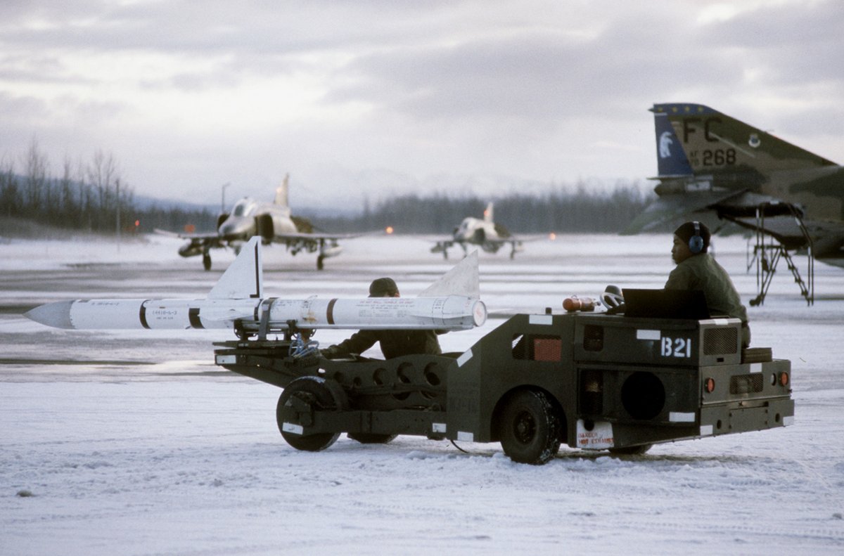 AIM-7E/F Sparrow air-to-air missile on bomb loader beside a USAF F-4E Phantom II aircraft