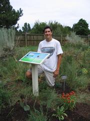 Eagle Scout standing in a prairie garden holding a wooden plaque