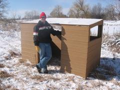 Young Eagle Scout observing wildlife from a wooden viewing blind in a natural forest setting