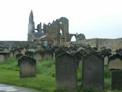 Ruins of Whitby Abbey with church tower and surrounding buildings under cloudy sky