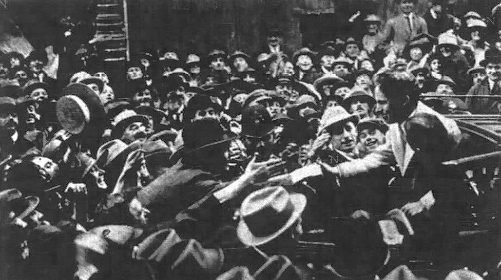 Charlie Chaplin exiting a cab at the Ritz Hotel in London in 1921 with crowds and police assistance