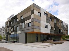 Front view of Popakademie building with glass facade and surrounding trees