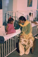 Woman and two children sitting in the children's ward at All-India Institute of Medical Sciences in New Delhi during Jacqueline Kennedy's visit