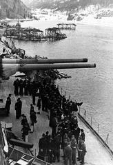 German battleship Tirpitz crewmen aboard moored in Norwegian fjord with 380mm gun turret trained abeam and camouflage floats nearby, circa 1942-44