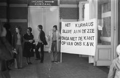 Black and white photo of EMS shareholders' annual meeting at Kurhaus with protest sign demanding Kurhaus to remain