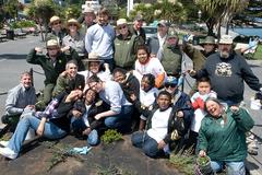 Children and adults smiling and posing near a newly planted native species garden in Aquatic Park