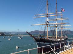 Square-rigger ship Balclutha docked in Aquatic Park Cove with Golden Gate Bridge in the background