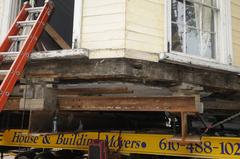 Close-up of bottom of house on beams showing windows and wooden planks during lift and move