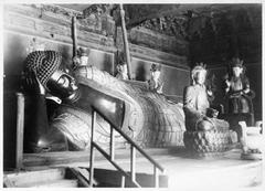 Historic Reclining Buddha statue at the Wafu Temple nestled among lush green trees on a stone-paved slope near Beijing.