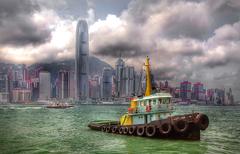 Tugboat sailing in Victoria Harbour with city skyline in the background