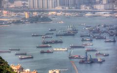 Boats in the harbor of Hong Kong with city skyline and green mountains in the background