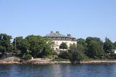 View of Waldermasudde from the water with rocky shoreline and greenery