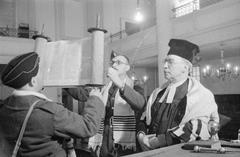 A soldier and airman raising the Torah under the supervision of Reverend Hermann Mayerowitsch at the Great Synagogue in London in 1941