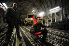 U.S. Air Force Chief Master Sgt. marshaling forklift loading generator onto C-17 Globemaster III at MacDill Air Force Base