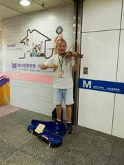 Street musician playing violin at Taipei Main Station underground metro square stair entrance