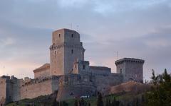 View of Assisi Rocca Maggiore castle perched on a hill with clear sky background