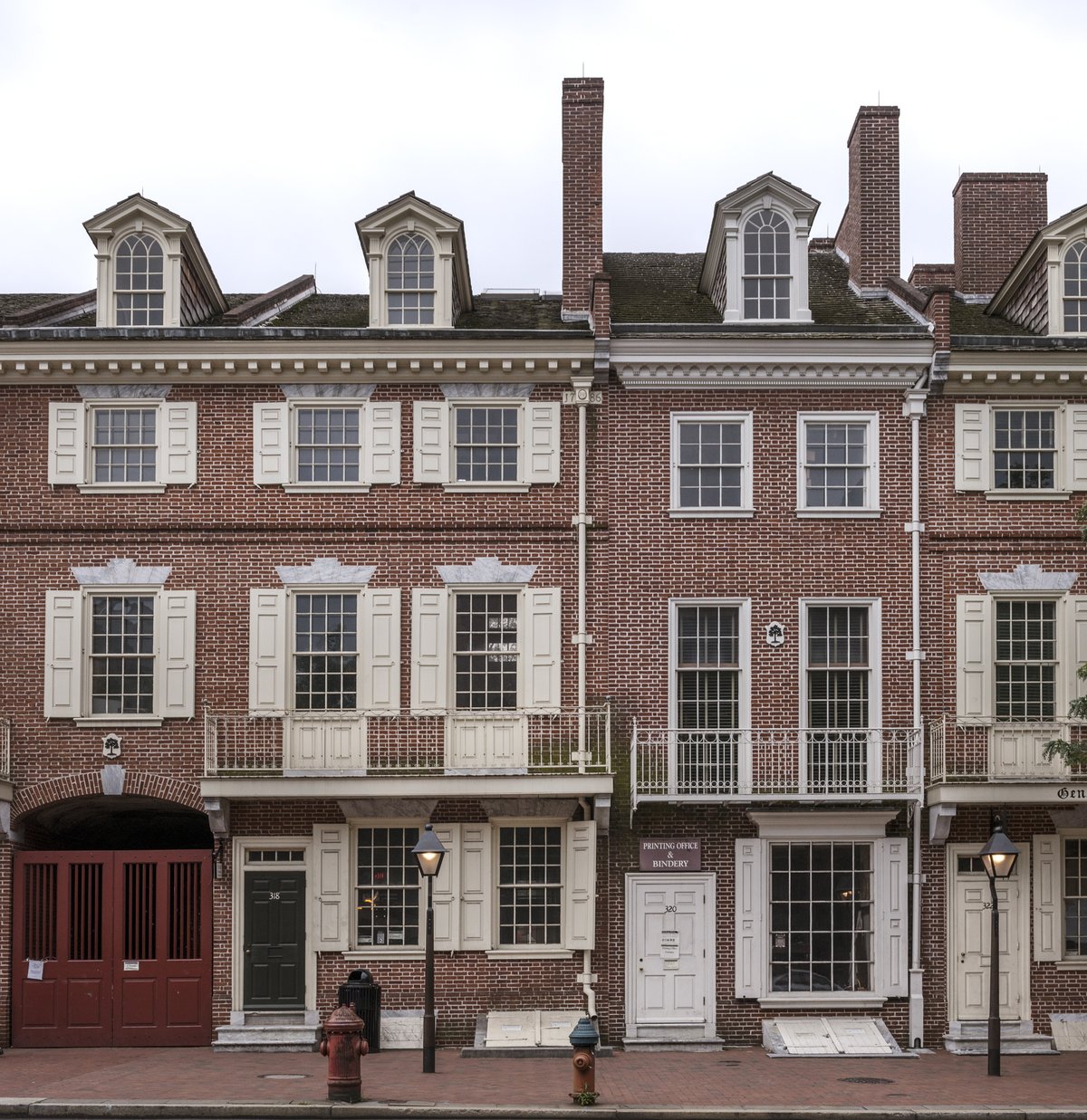 Red brick row houses with an arched brick passageway and red gate entrance to Franklin Court on Market Street