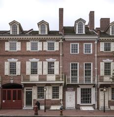 Red brick row houses with an arched brick passageway and red gate entrance to Franklin Court on Market Street