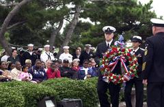 Sailors of USS Cole bearing a ceremonial wreath at USS Cole memorial on Naval Station Norfolk