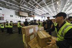 Sailors on USS Abraham Lincoln moving supply pallets in hangar bay