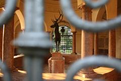 Hubertusbrunnen fountain in Munich with a historic iron grid surrounding it