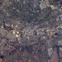 Satellite image of Soccer City stadium in Johannesburg with nearby slag piles, Soweto settlement, industrial park, and a golf course