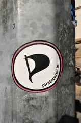 Sticker of Piratepartei Luxembourg on a surface, showing pirate symbol with red and black colors