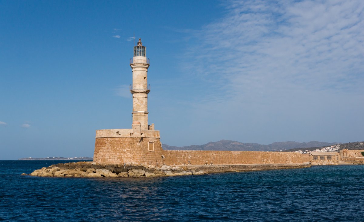 Chania lighthouse on a rocky shore at sunset in Crete Greece