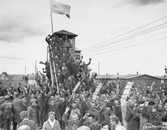 Survivors in striped uniforms at Allach sub-camp of Dachau greet arriving U.S. troops during liberation in April 1945