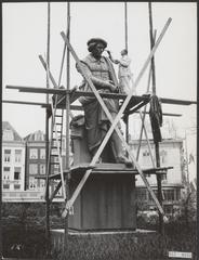Black and white photo of the Rembrandt statue on Rembrandtplein in Amsterdam being painted during the 350th anniversary celebration of Rembrandt's birth in 1956