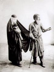 Blind beggar sitting with a woman and child in historical Iran