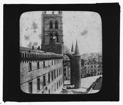 Late 19th-century view of Cathédrale Saint-Pierre in Montpellier, featuring the cathedral's bell tower and portal seen from Rue de l'Ecole de Médecine with the medical school in the foreground and houses in the background