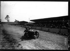 Early 20th century cyclecars racing at Circuit de la Sarthe in front of grandstands