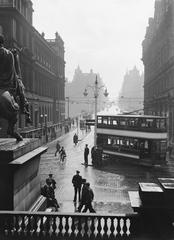 Rainy day intersection in Edinburgh city with vintage cars and pedestrians 1934