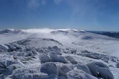 Morning views from the summit of Mount Kosciuszko in Kosciuszko National Park, New South Wales, Australia with clear blue sky and vast mountain ranges