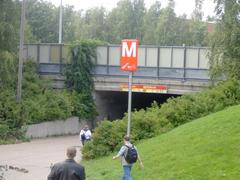 Entrance of Kulosaari metro station in Helsinki surrounded by lush trees