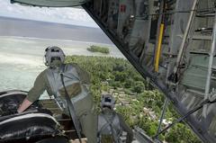 Loadmasters of the 36th Airlift Squadron looking out at a Micronesian island during Operation Christmas Drop
